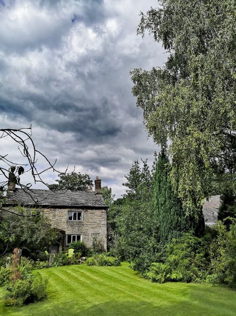 Goytside Farmhouse and gardens under stormy skies