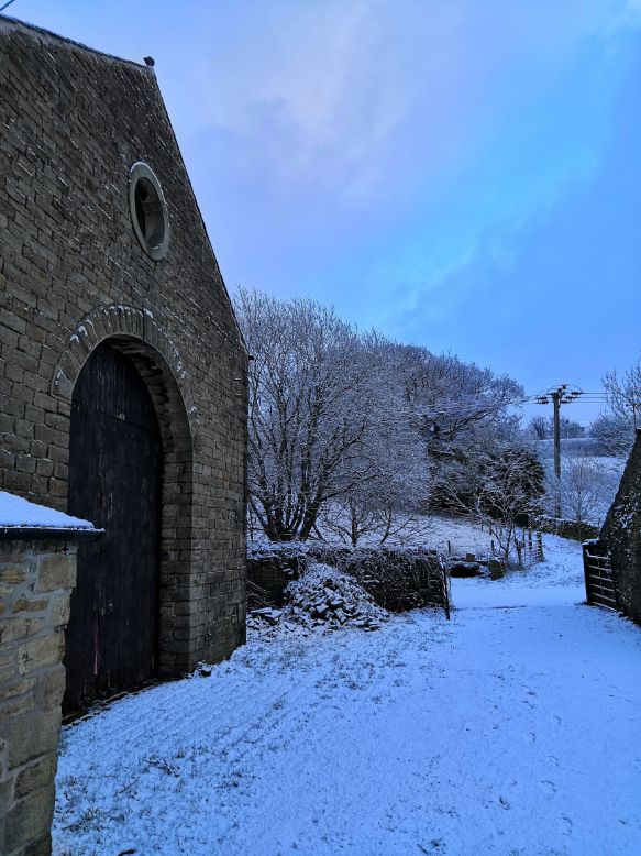 Snowy cobbled Goytside farmyard and barn